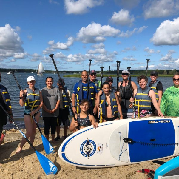 A group of people stand on the beach after a SUP paddle board tour on Cape Cod with RideAway Adventures