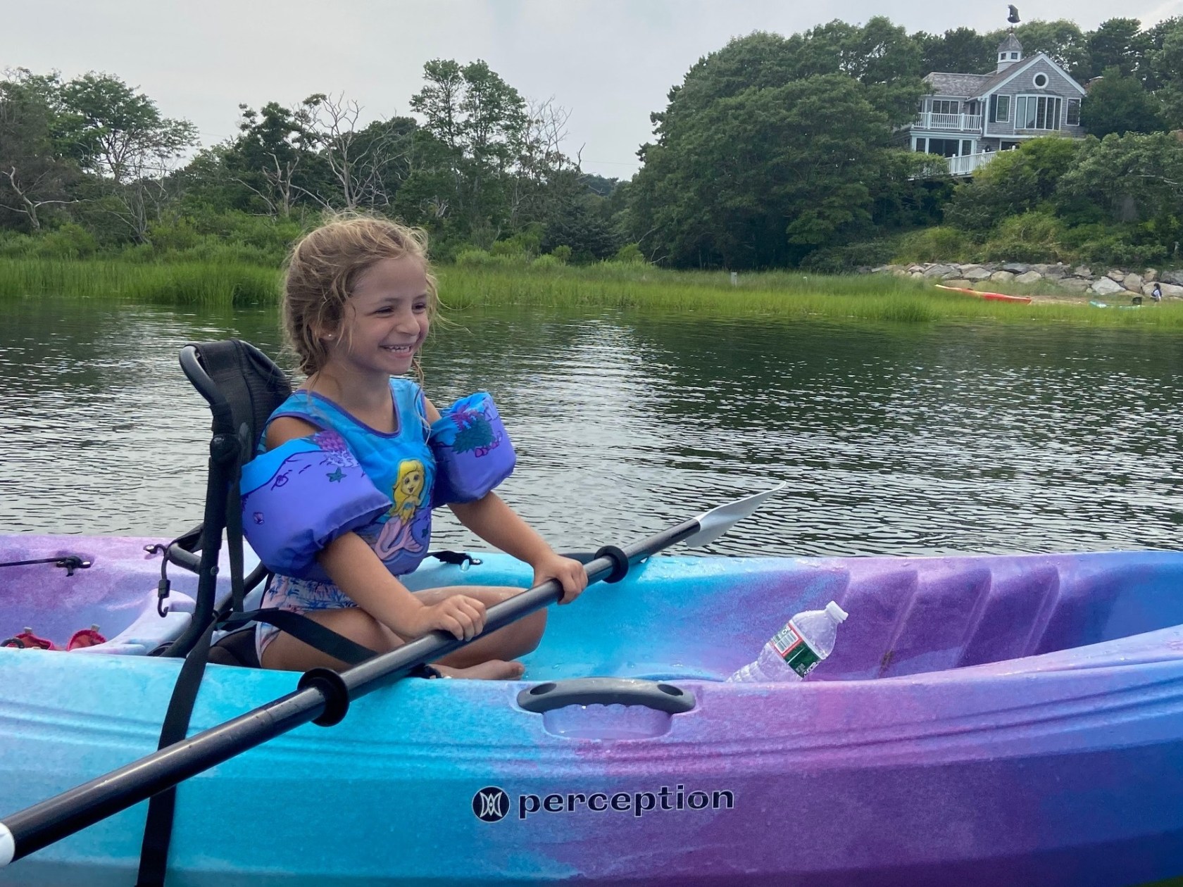 A young girl smiles as she learns how to kayak with RideAway Adventures during Kids Camp