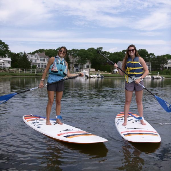 2 women enjoy a stand-up paddleboard tour on Cape Cod with RideAway Adventures