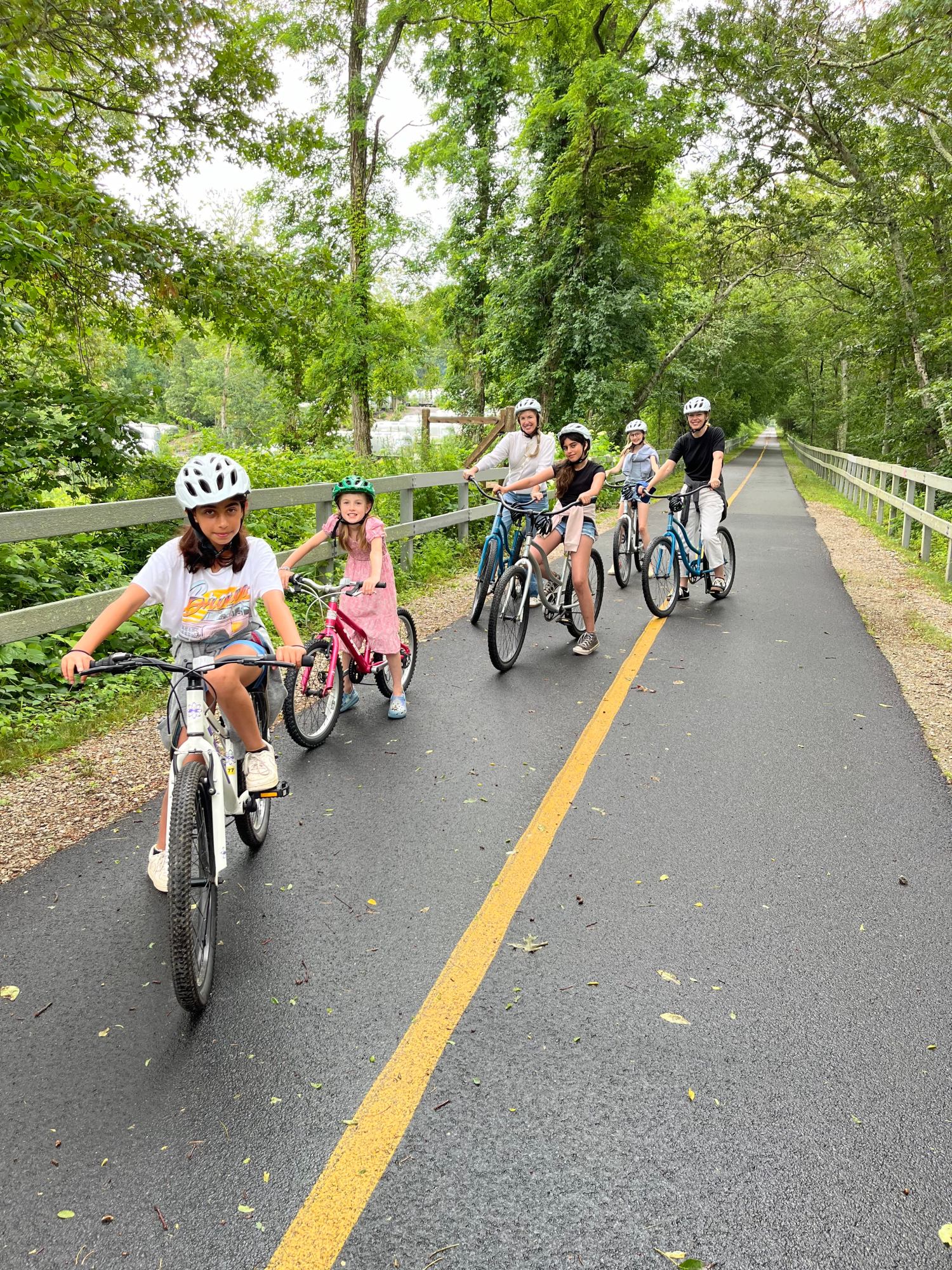 A group of kids and parents ride on a bike trail on Cape Cod after renting bikes with RideAway Adventures.